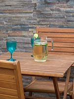 Jug and glasses on wooden table in urban garden