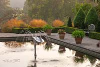 Italian garden with terracotta containers and pool with fountain, Borde Hill Garden, West Sussex, October.