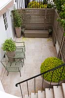 Basement terrace with Buxus containers and seats, London, April.