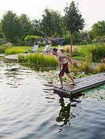 Boy about to jump from jetty into natural swimming pool
