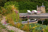 'Natural' swimming pool with marginal planting and waterlilies. Surrounded by gravel path plus wooden jetty. Also seating and entertaining space.