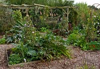 Potager with raised beds of vegetables and wigwams with sweetpeas
