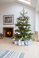 White colour themed Christmas tree in living room with fire 