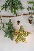 Close up detail of natural material Christmas decorations - branch decorated with stars, folliage and LED lights.
