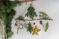 Natural material Christmas decorations - branch decorated with stars, wreath, foliage and LED lights in rustic setting