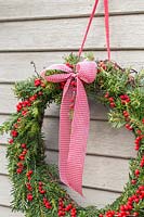 Festive Christmas wreath hanging in a rustic setting on a frosty morning