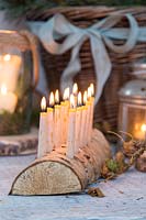 Close up detail of Lit Birch wood candle holder with beeswax candles