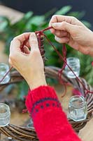 Close up detail of using string to suspend natural wreath base from the wooden pole