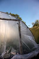 Replacing the polythene cover of a polytunnel - tensioning the new sheet around the door frame