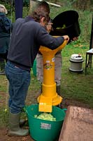 Speidel Electric Apple Mill in use at Community apple juicing day in Sampford Peverell, Devon, late October - feeding apples through the mill