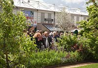 Visitors to the RHS Chelsea Flower Show looking at a Garden on Main Avenue. The Homebase Garden, Designer Adam Frost