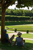 A couple sitting in the shade in the gardens at the Chateau de Villandry, Loire Valley, France. A UNESCO World Heritage Site