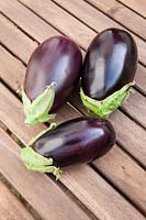 Three aubergines on a wooden table