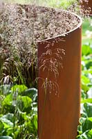 Contemporary garden with curved rusted corten steel panel and Deschampsia cespitosa 'Bronzeschleier' grasses RHS Hampton Court