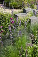 Rectangular granite stone blocks surrounded by planting of perennials and grasses including Stipa tenuissima, Nepeta, Cirsium