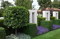 Formal contemporary garden with white stone arches and cube shaped Bay Tree and Box Buxus with Lavandula - Lavender