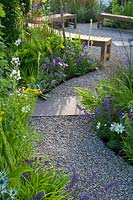 Contemporary garden with gravel path and circular seating area with wooden benches. Designers Catherine Chenery Barbara Harfleet