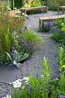 Contemporary garden with gravel path leading to seating area with wooden benches. Designers: Catherine Chenery Barbara Harfleet