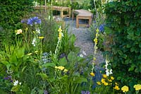 Contemporary garden with gravel path and seating area with wooden benches Designers: Catherine Chenery Barbara Harfleet