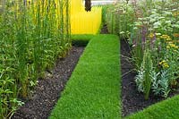 Grass path running between garden borders. The World Vision Garden. Designer: John Warland. RHS Hampton Court Flower Show
