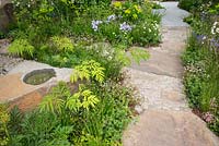 Woodland planting, stone path and boulder in The M and G Garden, RHS Chelsea Flower Show 2016. Designer Cleve West.