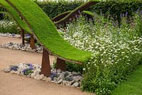 Undulating waves of artificial turf, underplanted with Anemone blanda and wild flowers. RHS Hampton Court flower Show
