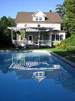 House with verandah with white painted furniture looking to swimming pool in the Hamptons Long Island USA