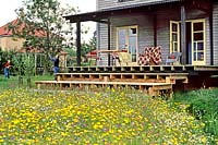 Verandah steps leading down to a colourful wildflower meadow Father child playing badminton on lawn Furniture Diss, Norfolk