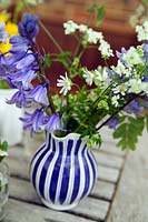 Bunch of newly picked spring wildflowers in blue striped vase on table