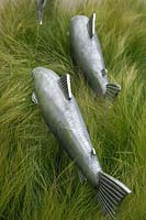 Metal fish in border of Stipa tennuissima on the Gaze Burvill stand at RHS Chelsea Flower Show 2012