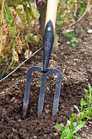 Gardener using a De Wit Small Fork with Long 'T' Handle to prepare soil