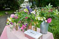Posies of colourful cut flowers for sale on a roadside table with honesty  box