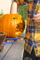 Boy is carving a Halloween pumpkin