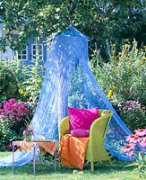 Green wicker chairs under blue mosquito net