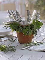 Garland of herbs to clay pot with cutlery