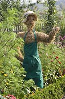 Scarecrow from straw gardener's apron in cottage garden