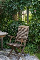 Wooden chair on a small, paved terrace in front of Garden House