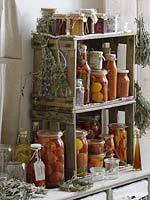 Canned tomatoes, peppers, vinegar and herbs in selfmade shelf