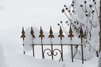 Schmieder iron fence element and faded perennial thick snow in the winter garden