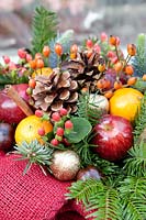 Christmas arrangement with Hypericum, brushwood, oranges, cones and apples