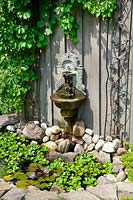 Water fountain and little pond with aquatic plants