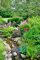 Gardenscene with little stream, perennial border and shrubs