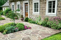 Front yard with various shrubs, perennials and natural stone walkway,