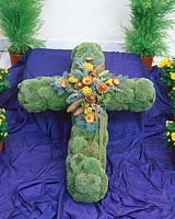 Kreuz aus Moss mit Zapfen und gelber Achillea dekoriert