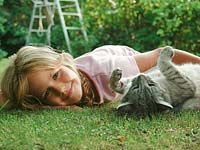 Girl playing with a cat on the lawn