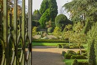 The Abbey House, Malmesbury, Wiltshire, UK ( Pollard ). Autumn in large garden with clipped Yew hedging and topiary, gateway