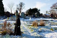 Allotment on cold and snowy winter's day. Scarecrow