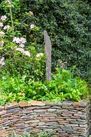 Chelsea Flower Show 2006, London, UK. 'A Cornish Oasis' ( des. Pickard Shool of Garden Design 2005 graduates ) standing stone in border with stone wall