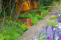 Chelsea Flower Show 2006, London, UK. 'The Telegraph Garden' ( des. Tom Stuart-Smith ) brick pathway with metal water containers at edge.