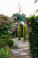 Caervallack, Cornwall, UK. ( McClary/Robinson ) Artists garden in summer, metal ornamental arch leading into paved garden